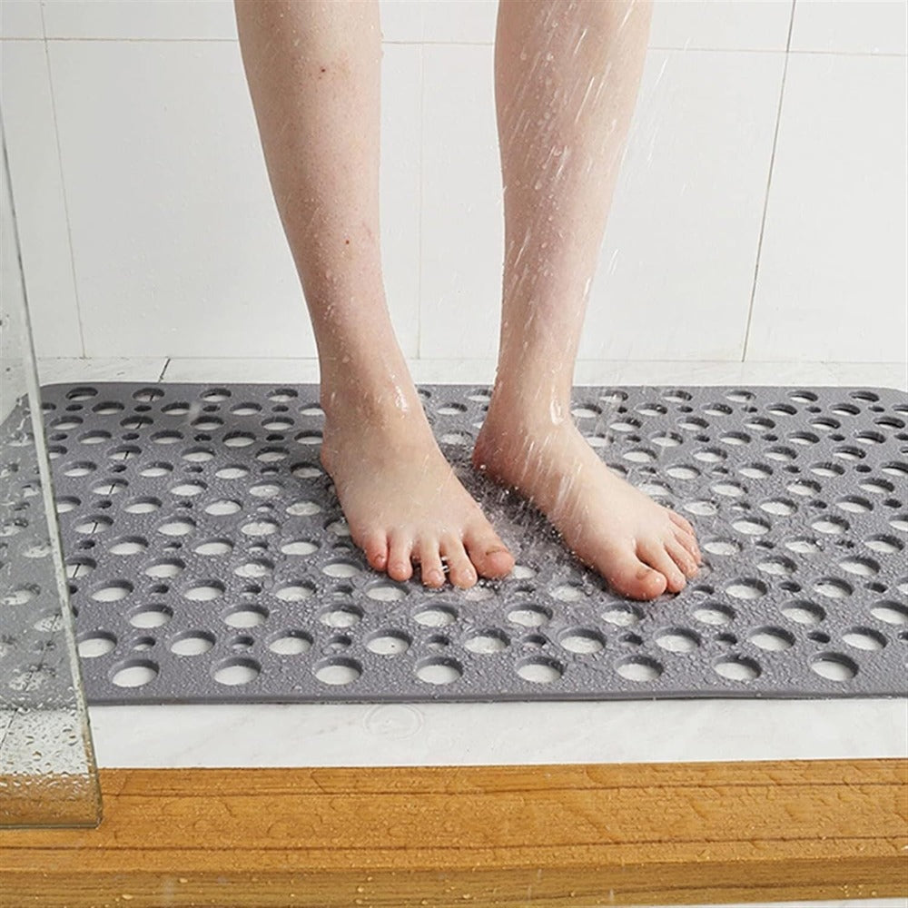 A person standing on a gray antibacterial suction shower mat in the shower stall, showing the non-slip surface designed for safety.