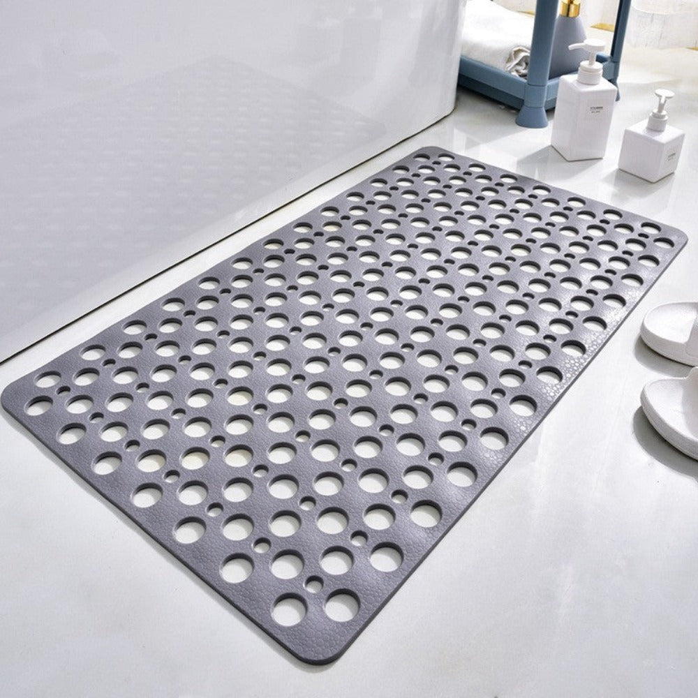 Grey antibacterial suction shower mat with drainage holes laid flat in a bathroom


