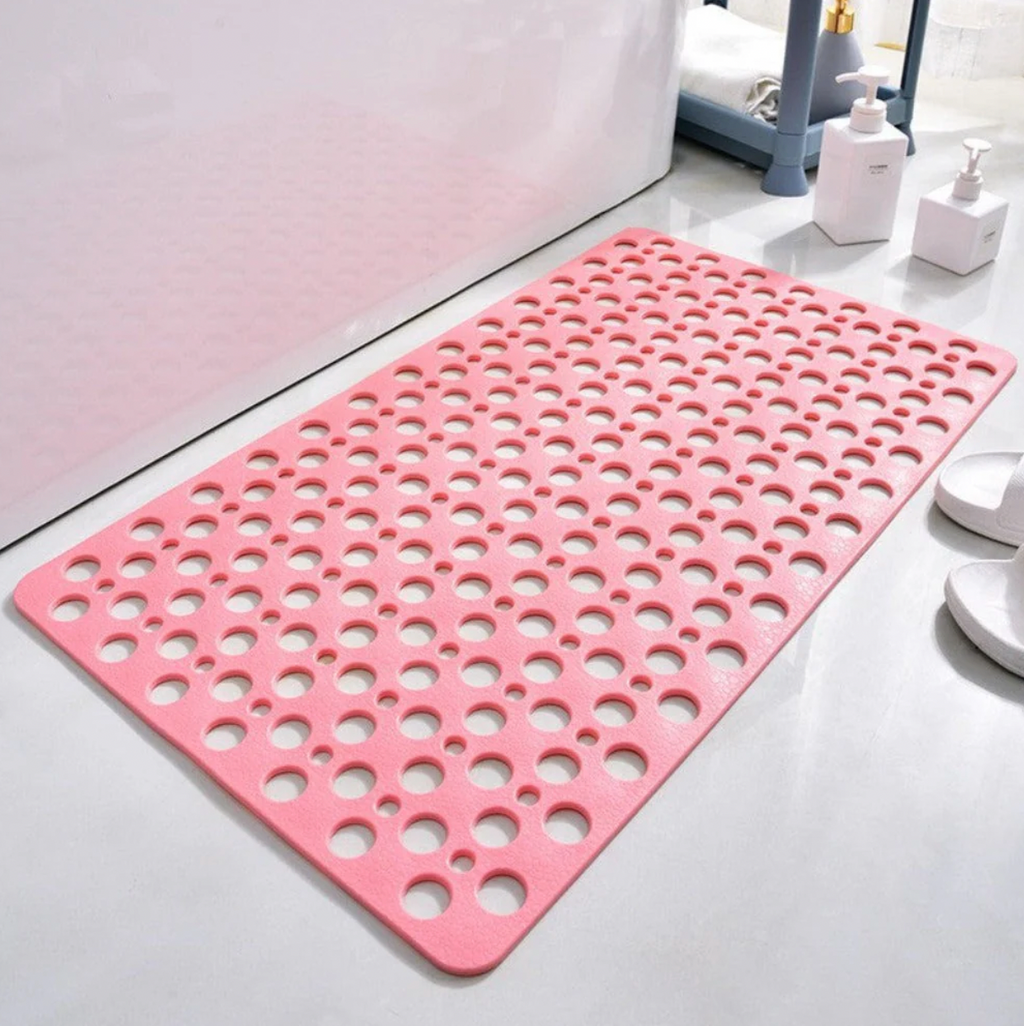 Pink antibacterial suction shower mat with drainage holes in a bright bathroom

