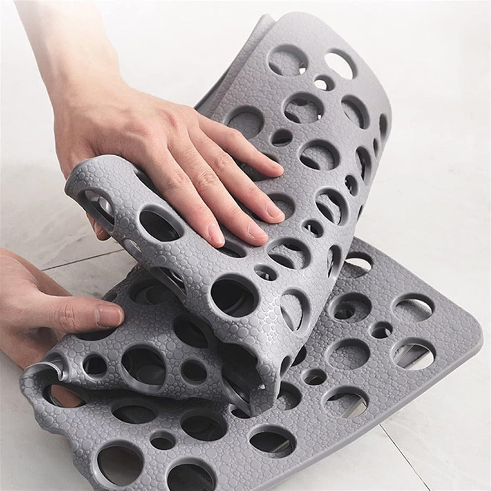Hands demonstrating the flexible, durable material of the grey antibacterial suction shower mat

